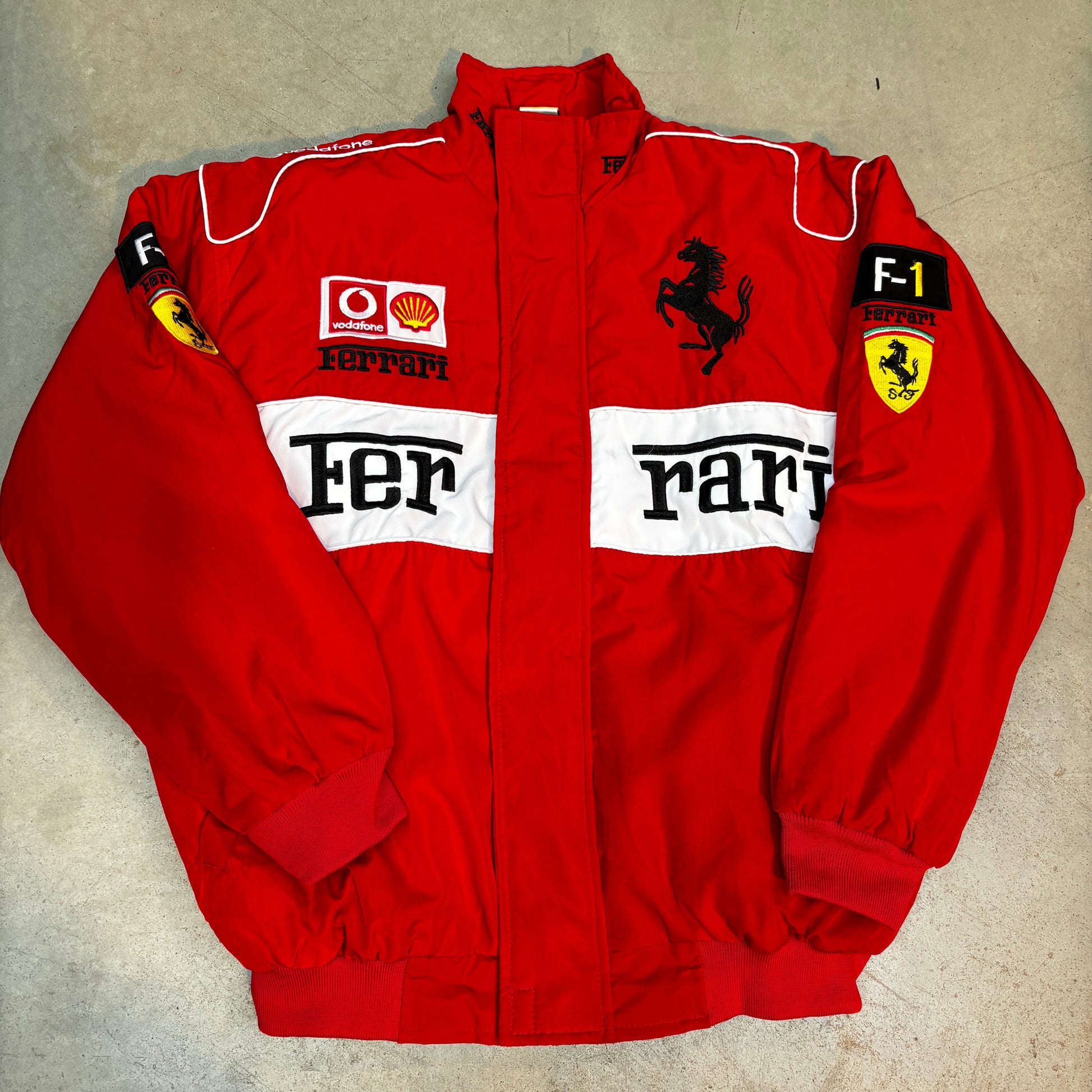Folded red ferrari racing suit with visible branding on a beige surface