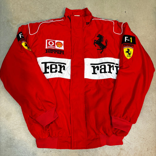 Folded red ferrari racing suit with visible branding on a beige surface